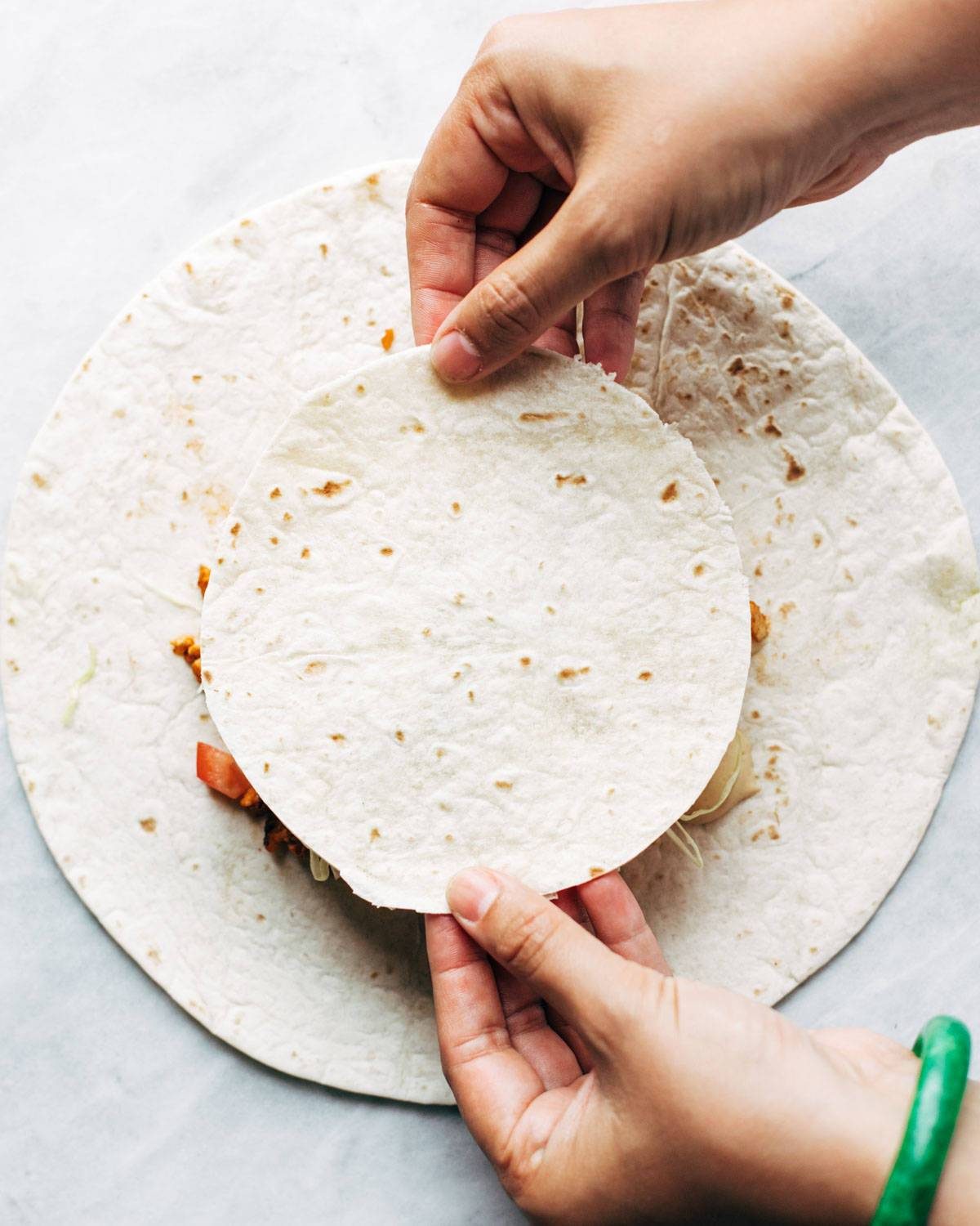 Adding tortilla to vegan crunchwrap supreme.